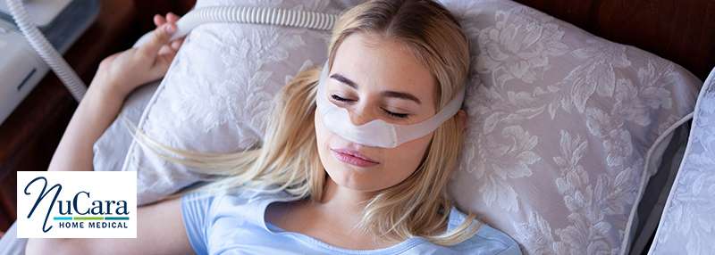 Woman sleeping with CPAP mask on and tubing in the background