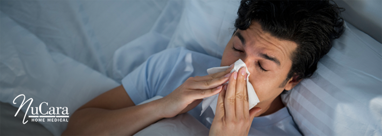 Man lying in bed blowing his stuffy nose