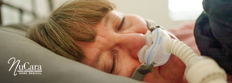 Woman lying on bed sleeping on her side with CPAP nasal mask on
