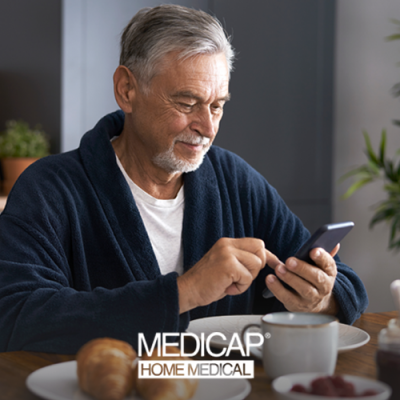 Older man looking at an app on his smartphone and smiling in his kitchen