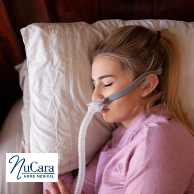 Woman sleeping on bed on her side with CPAP mask on and connected to a CPAP machine on the bedside table