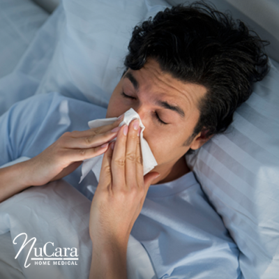 Man lying in bed blowing his stuffy nose