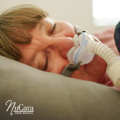 Woman lying on bed sleeping on her side with CPAP nasal mask on