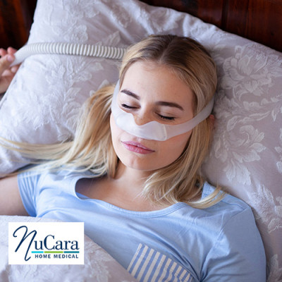 Woman sleeping with CPAP mask on and tubing in the background